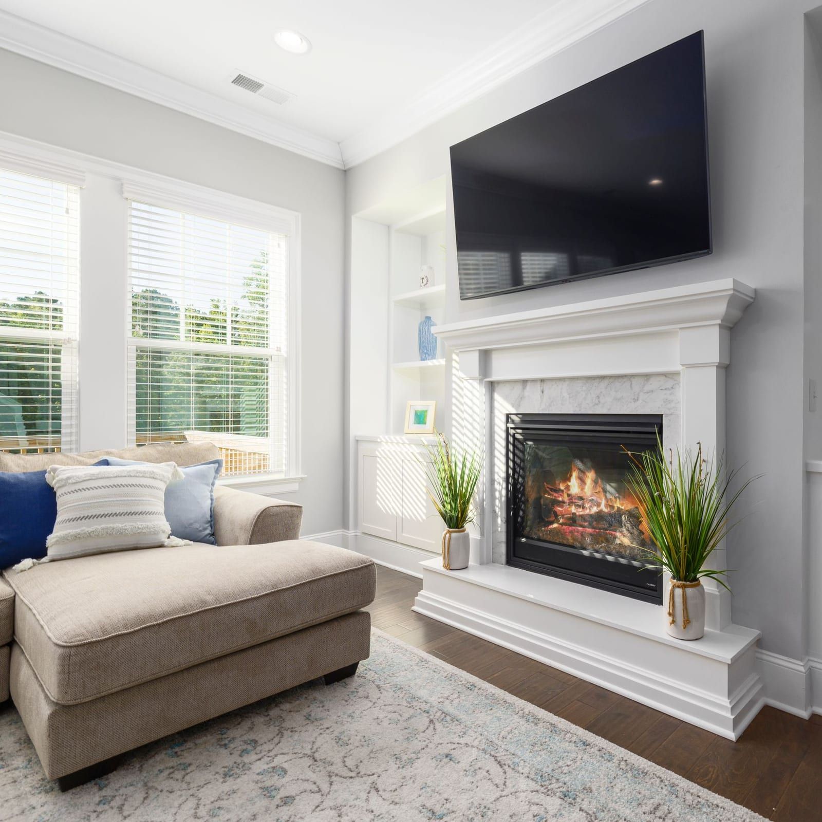 Living room with a TV mounted level above a white fireplace beside built-in shelving